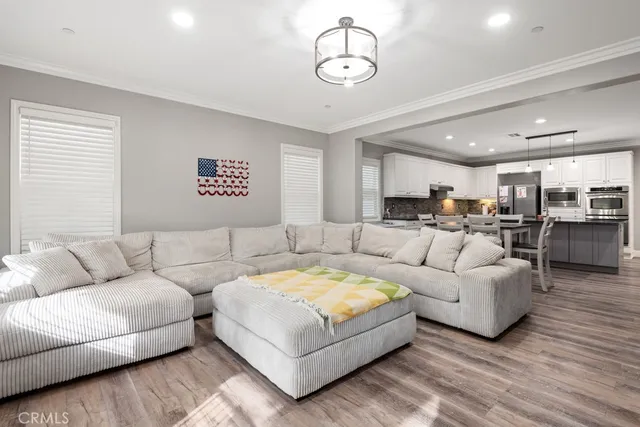 a living room with furniture kitchen view and a chandelier