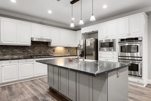 a kitchen with stainless steel appliances granite countertop a sink a stove and a refrigerator