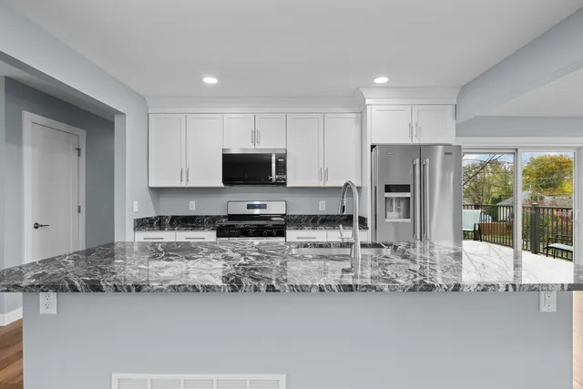 a kitchen with stainless steel appliances granite countertop a sink refrigerator stove and microwave