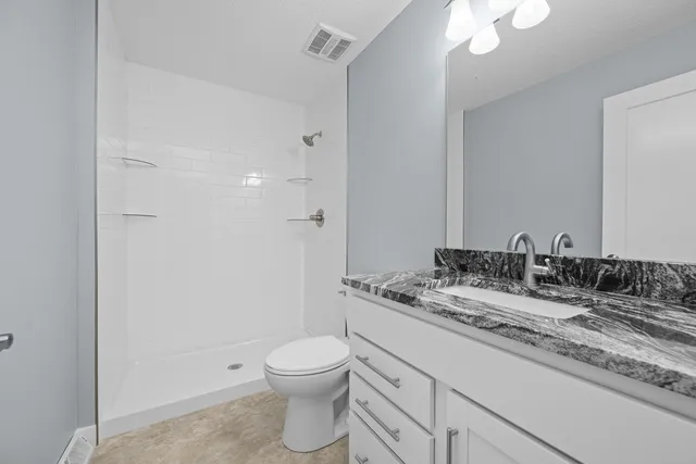 a bathroom with a granite countertop sink a toilet and a mirror
