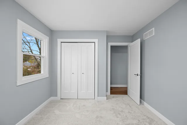 a view of an empty room with closet and a window