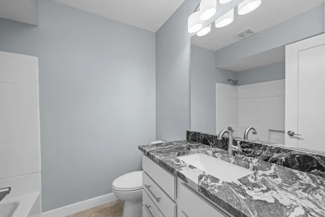 a bathroom with a granite countertop sink a toilet and a mirror