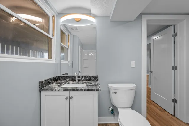 a bathroom with a granite countertop toilet a sink and a mirror