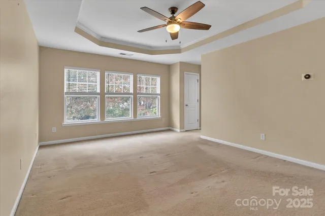 an empty room with windows and ceiling fan