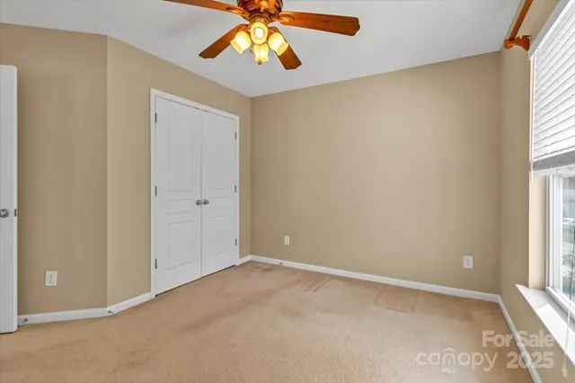 an empty room with windows and chandelier fan