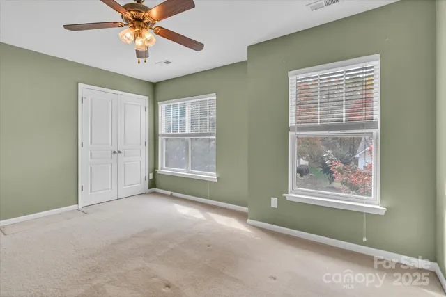 an empty room with windows and fan