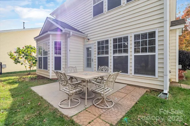 a patio with a table and chairs and potted plants