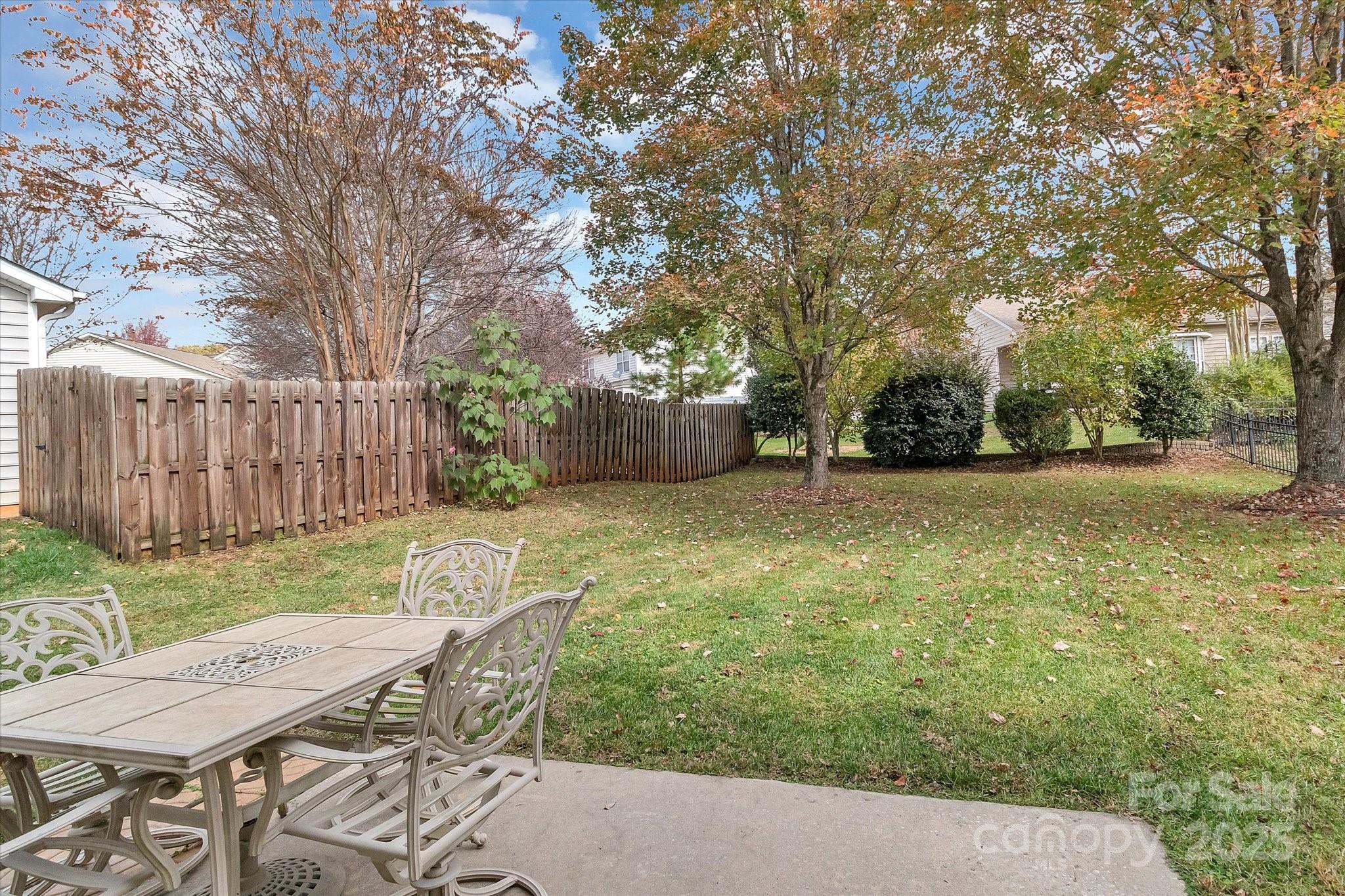 297 Sand Paver Way Fort Mill, SC 29708 - Photo 37 of 39 a view of a patio with table and chairs with wooden fence and large trees