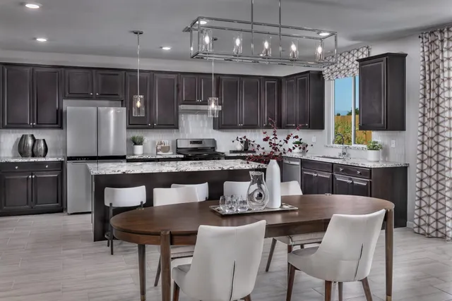 a kitchen with a dining table chairs refrigerator and microwave