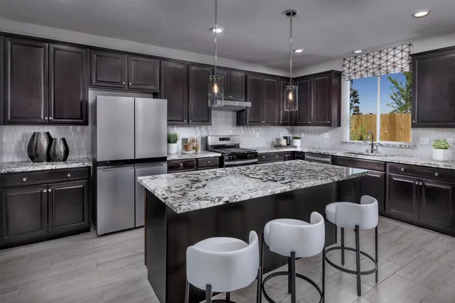 a kitchen with kitchen island granite countertop a sink and a refrigerator