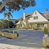 a view of a white house with a fountain plants and wooden fence