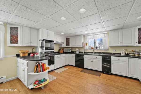 a kitchen with stainless steel appliances kitchen island granite countertop a sink cabinets and wooden floor
