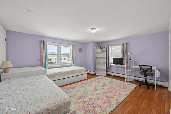 a spacious bedroom with a bed and wooden floor