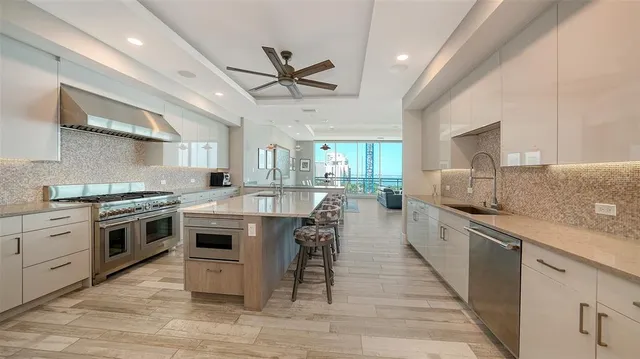 a kitchen with stainless steel appliances kitchen island granite countertop a sink a stove and a wooden floors