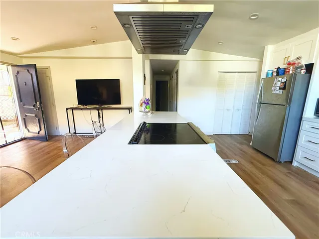 a living room with stainless steel appliances furniture a fireplace and a flat screen tv