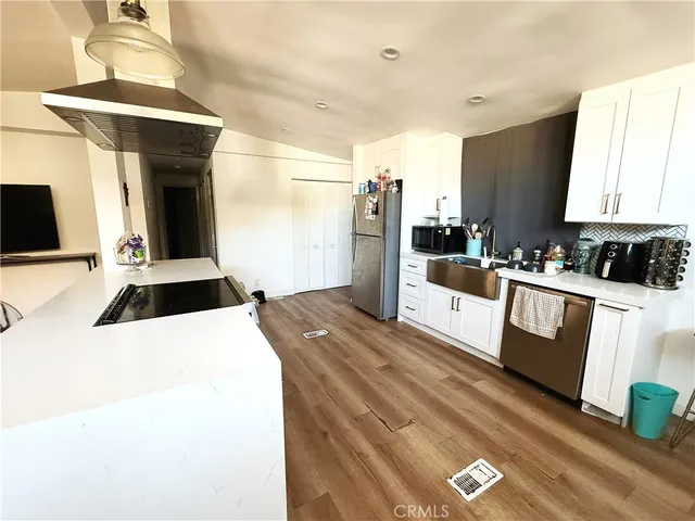 a kitchen with stainless steel appliances a stove a refrigerator a sink and white cabinets