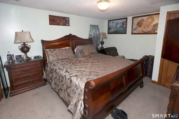 a bedroom with a bed and a lamp on dresser