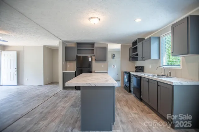 a kitchen with granite countertop a sink cabinets and wooden floor