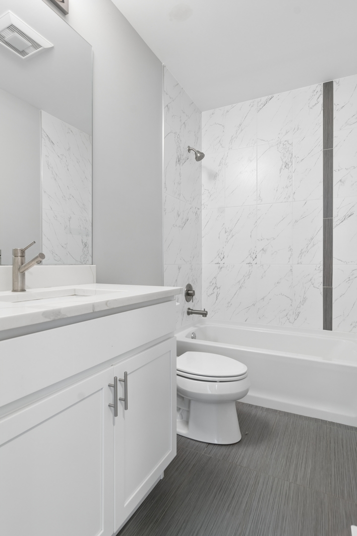 4845 North Keystone Avenue, Unit 2N Chicago, IL 60630 - Photo 20 of 21 a bathroom with a white toilet sitting next to a white sink and a wooden floor
