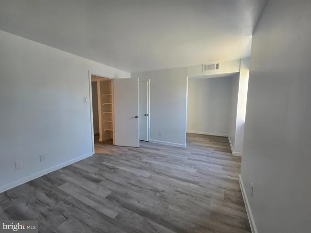 a view of an empty room with wooden floor and closet