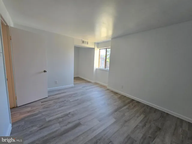 a view of an empty room with wooden floor and window