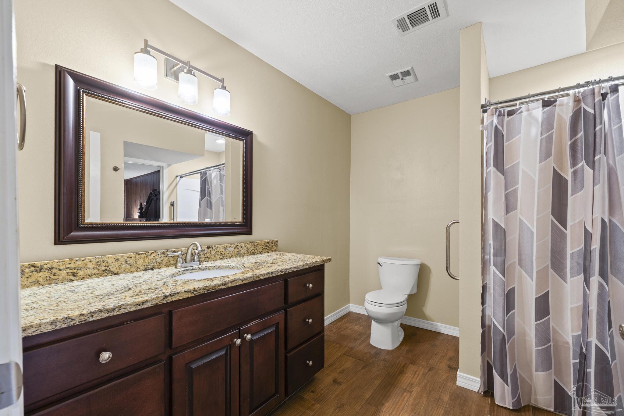 4960 Hyatt Lane Pace, FL 32571 - Photo 11 of 23 a bathroom with a granite countertop sink a toilet and a mirror