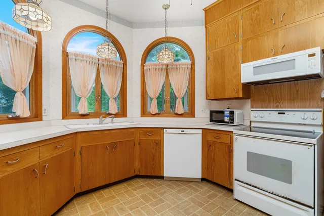 a kitchen with stainless steel appliances granite countertop a stove a sink and a dishwasher with wooden cabinets