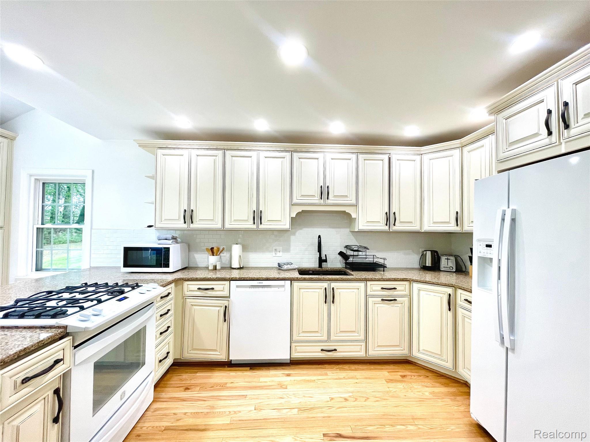 60 Devon Road Bloomfield Hills, MI 48302 - Photo 21 of 50 Kitchen featuring light-toned cabinetry, granite countertops, hardwood flooring, recessed lighting, and a white subway tile backsplash