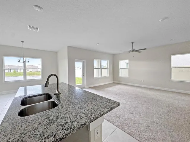 a kitchen view with granite countertop a stove a sink a window and dining table