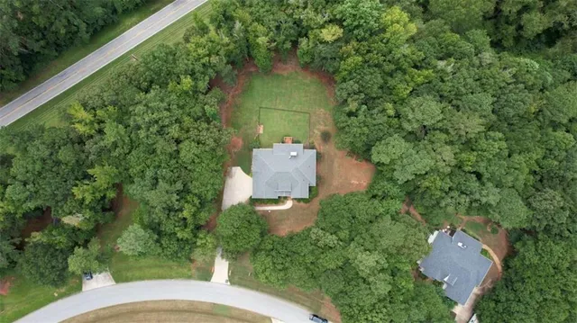an aerial view of a house with outdoor space and trees all around