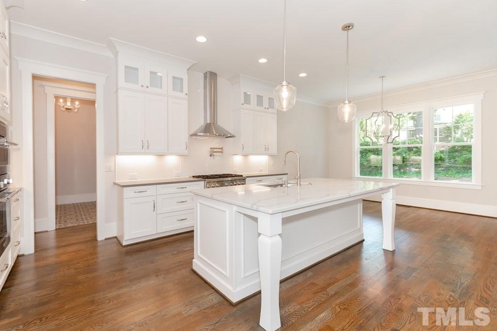 3319 Lake Boone Trail Raleigh, NC 27607 - Photo 5 of 30 a kitchen with a stove a sink a refrigerator and white cabinets with wooden floor