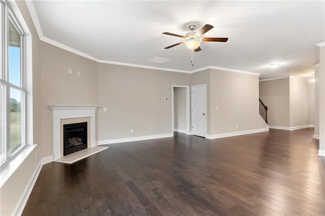 a view of an empty room with wooden floor fireplace and a window
