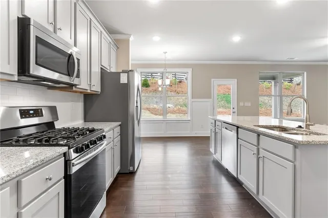 a kitchen with stainless steel appliances granite countertop a stove a sink and a microwave