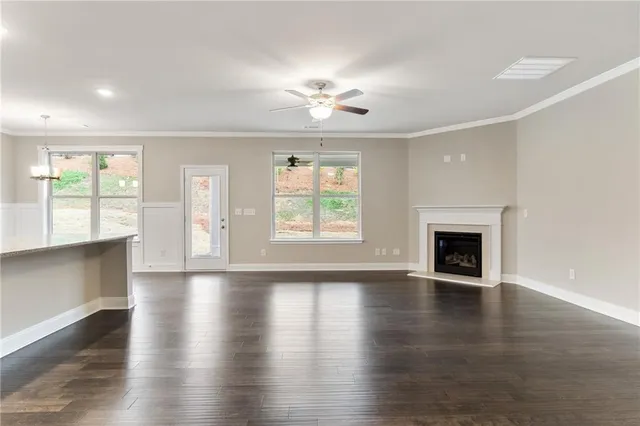 an empty room with wooden floor fireplace and windows