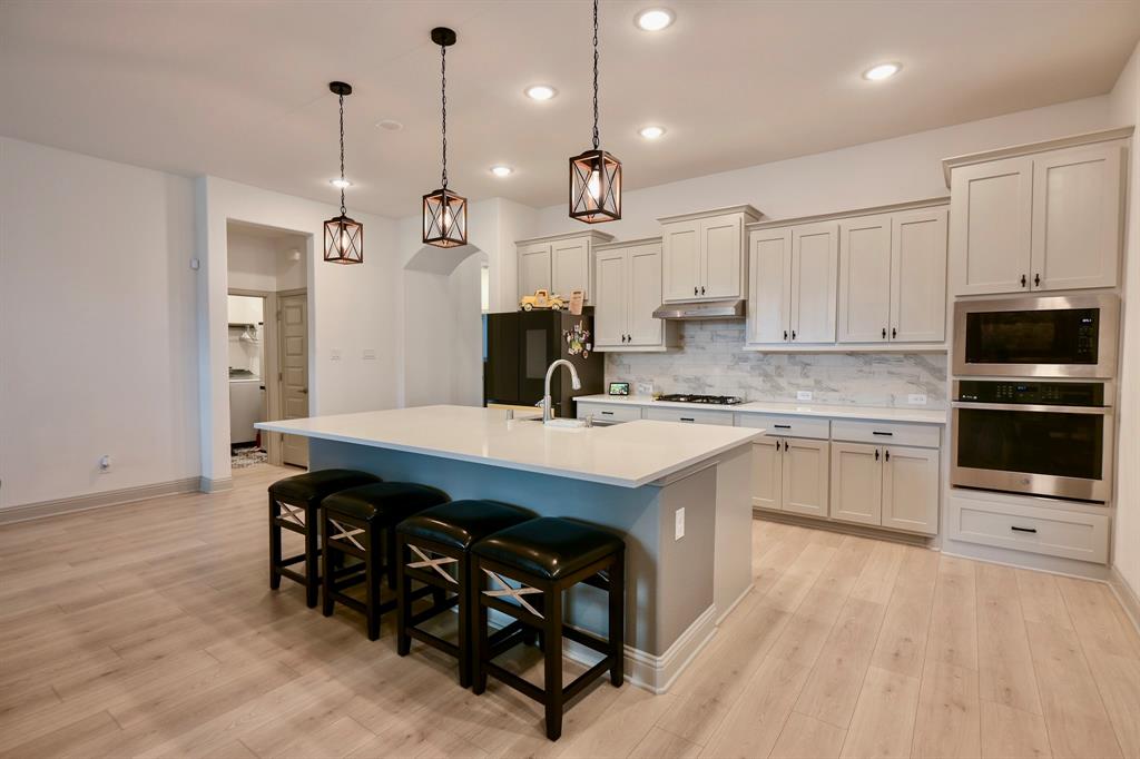 2609 Henley Way Venus, TX 76084 - Photo 19 of 40 a kitchen with kitchen island granite countertop a sink a stove a refrigerator and a island with wooden floor