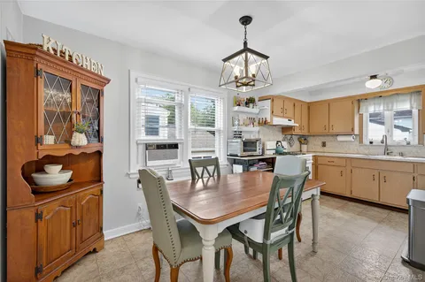 a dining room with stainless steel appliances kitchen island granite countertop a table chairs and a refrigerator