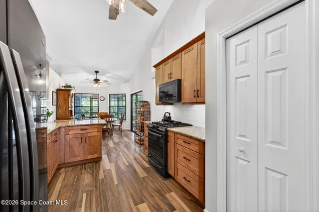 a kitchen with stainless steel appliances granite countertop a refrigerator a stove top oven a sink dishwasher and wooden cabinets with wooden floor
