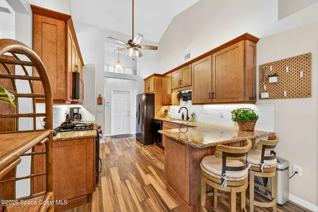a kitchen with stainless steel appliances kitchen island granite countertop a table chairs in it and wooden floors