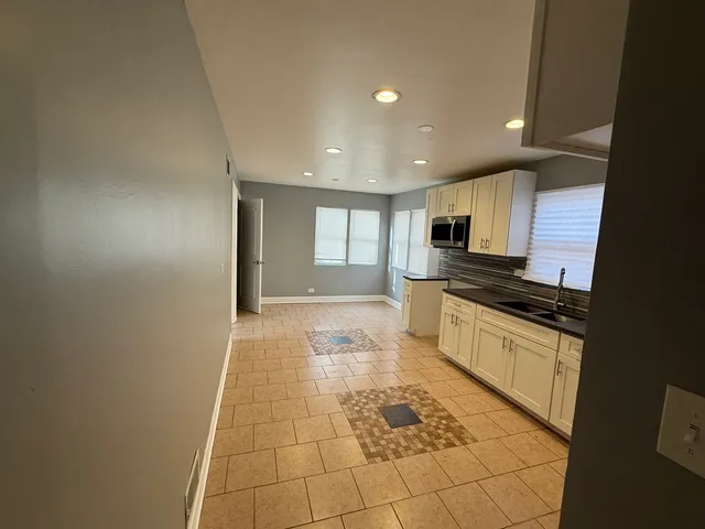 a large white kitchen with stainless steel appliances granite countertop a sink and cabinets