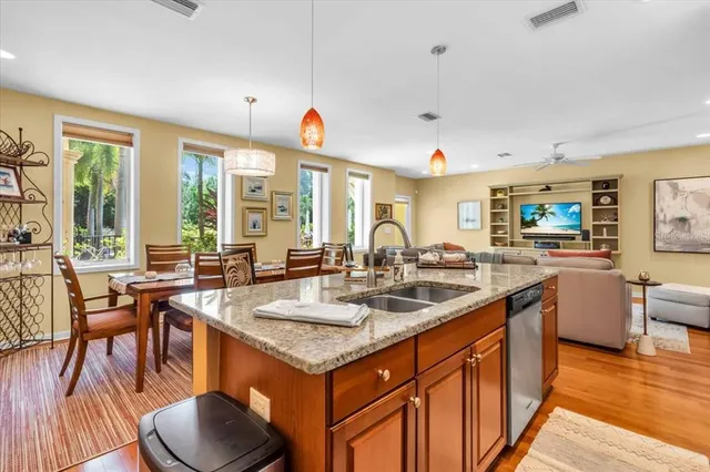 a dining hall with stainless steel appliances granite countertop a sink a stove a dining table and chairs with wooden floor