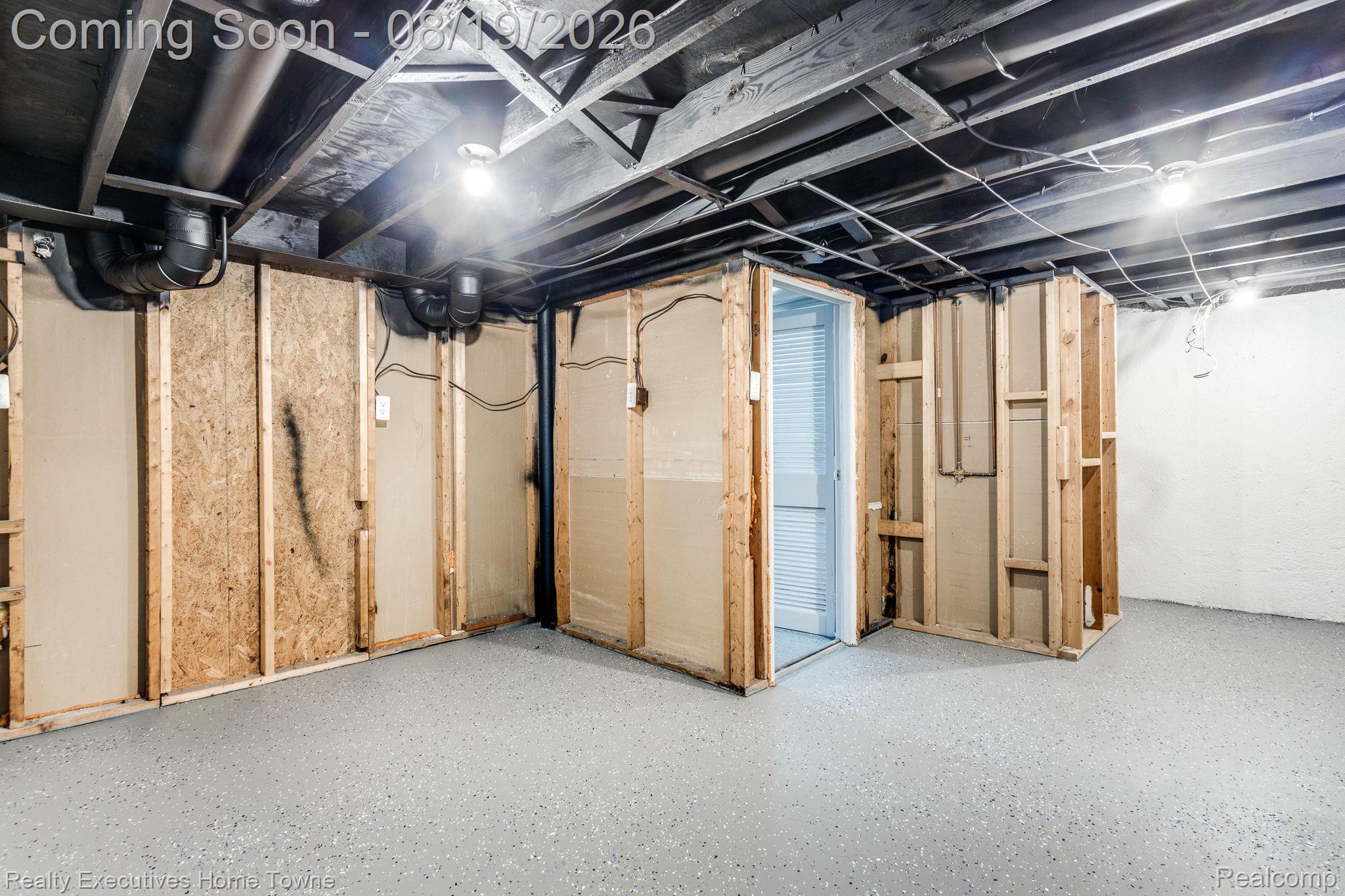 2448 Oakcrest Road Sterling Heights, MI 48310 - Photo 26 of 31 Unfinished room featuring exposed ceiling joists, light gray speckled flooring, partial wood framing, and a white louvered door