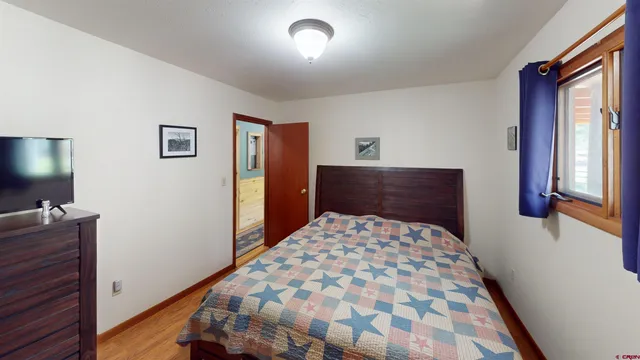 a bedroom with a bed and a flat tv screen on the dresser