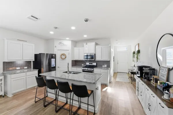 a kitchen with kitchen island granite countertop a sink a stove a refrigerator and island with wooden floor