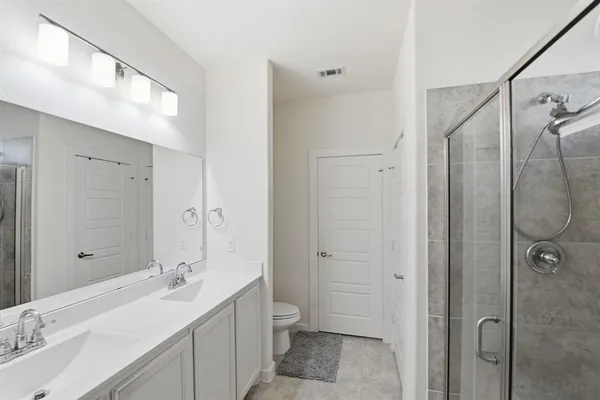 a bathroom with a double vanity sink toilet mirror and shower