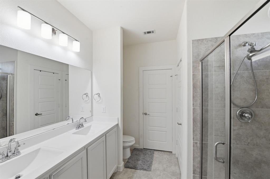 7645 Spring Drive Watauga, TX 76148 - Photo 20 of 28 a bathroom with a double vanity sink toilet mirror and shower