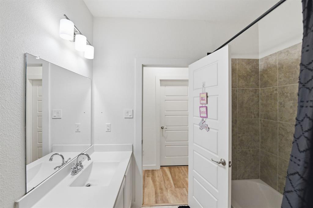 7645 Spring Drive Watauga, TX 76148 - Photo 25 of 28 a bathroom with a sink a mirror and a bathtub