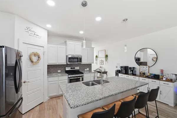 a kitchen with stainless steel appliances granite countertop a sink a stove a refrigerator with a dining table and chairs