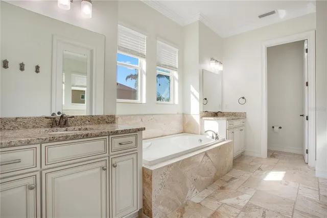 a spacious bathroom with a granite countertop sink a mirror and a bathtub