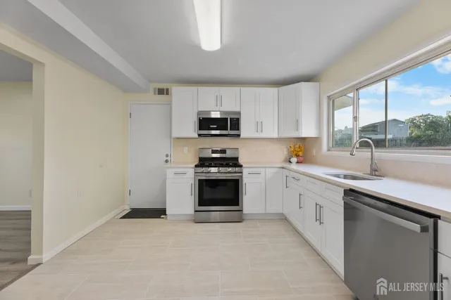 a kitchen with granite countertop a stove a sink and a microwave