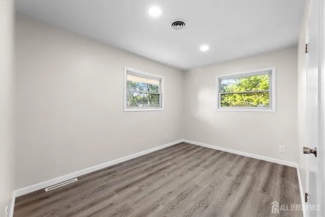 an empty room with windows and painting on the wall